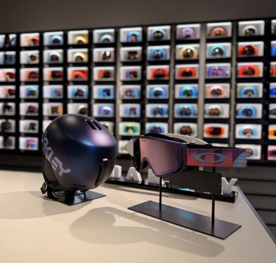 Photo du showroom Oakley Annecy-Le-Vieux avec fond flouté d'un mur de masques encastré lumineux et devant, exposition d'un casque et masque de ski